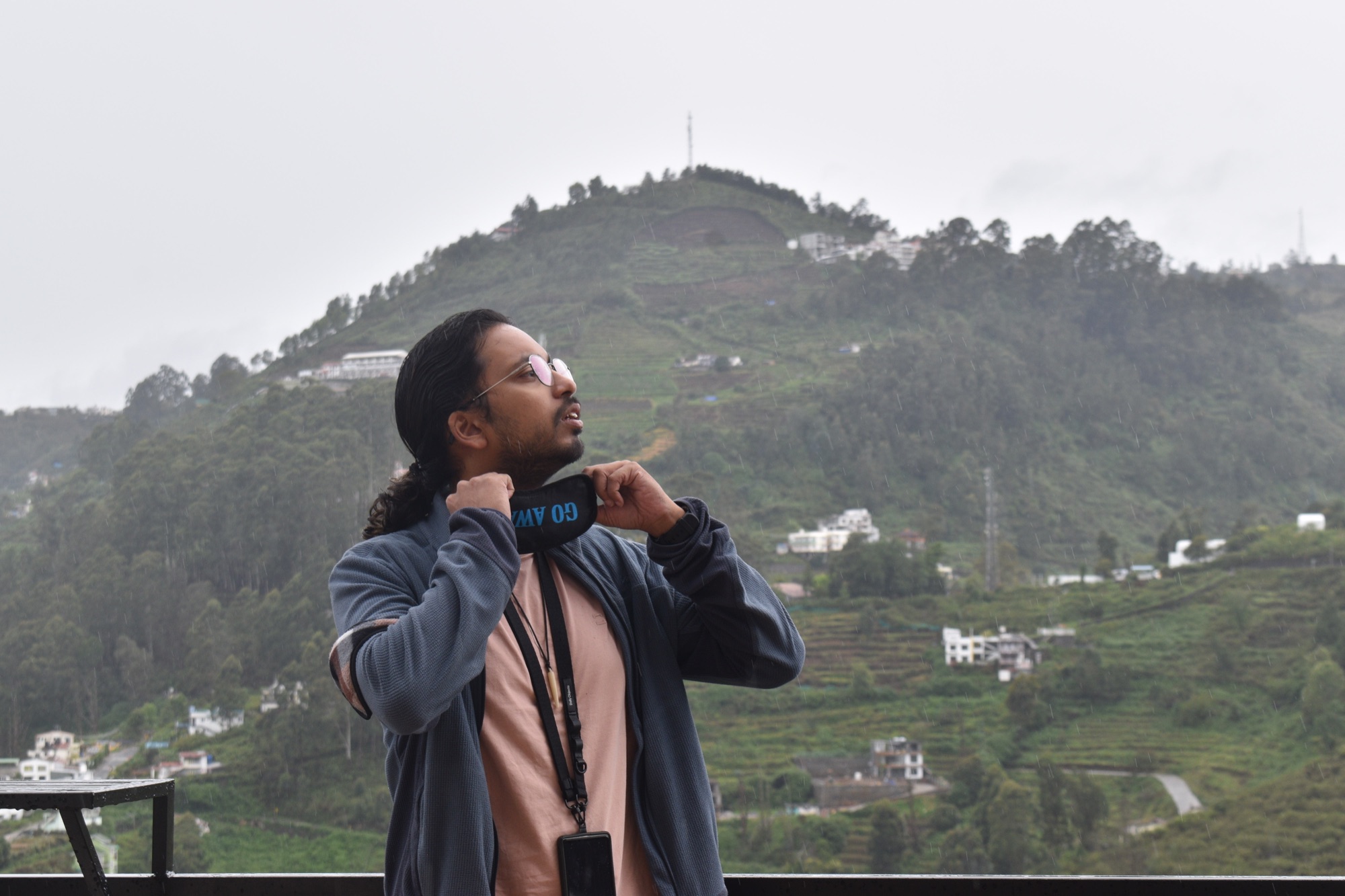 Aayush in front of terraced tea-garden hills on a misty morning